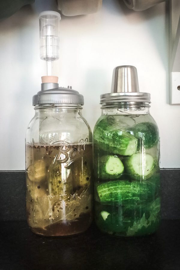 two jars of fermenting dill pickles on a counter