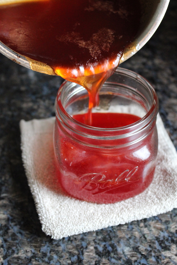 Pouring homemade prickly pear jelly into canning jars