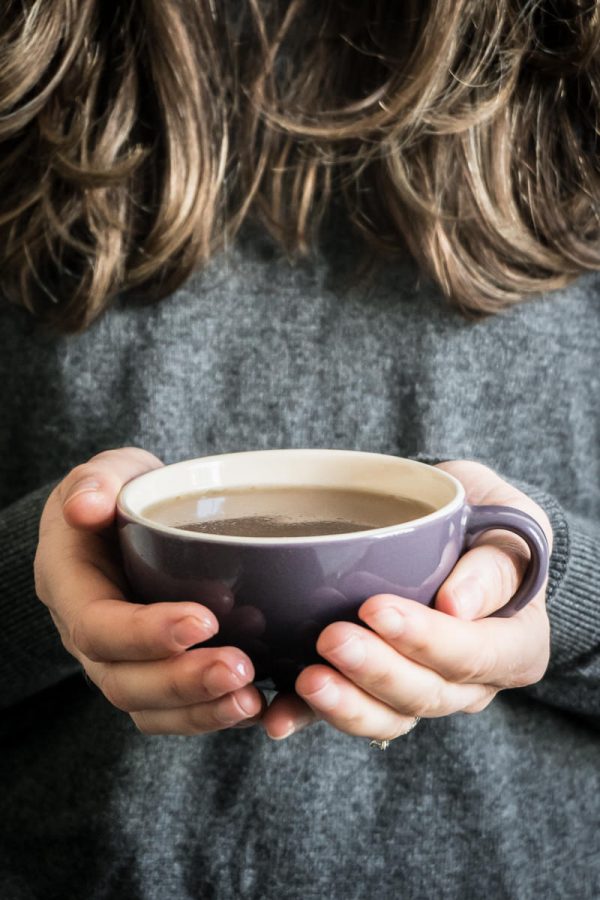 close up of hands holding a purple mug filled with bone broth