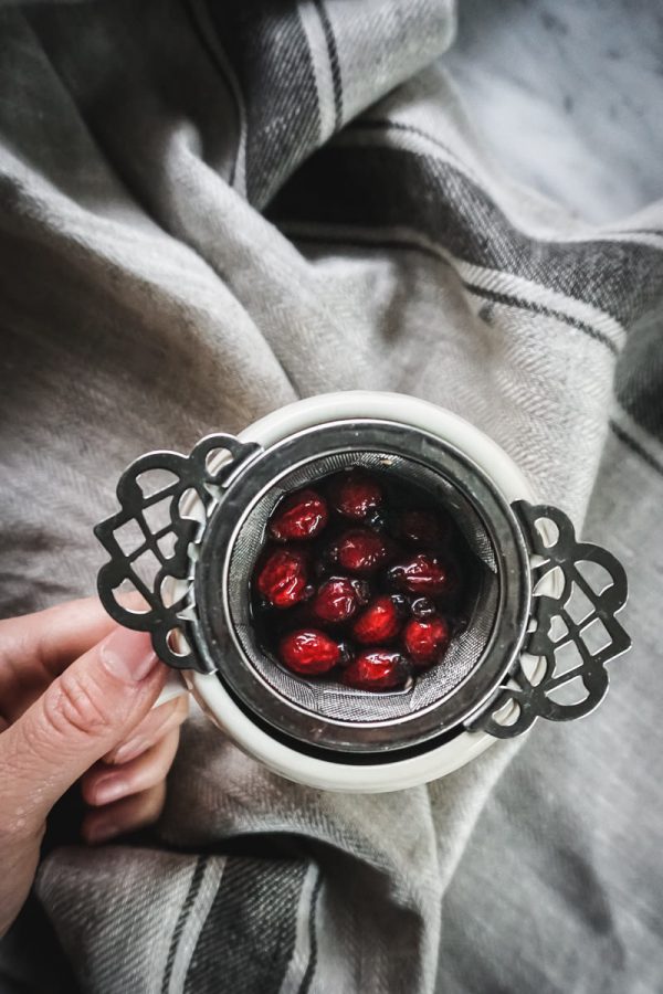 Herbal immunity tea steeping in a metal tea strainer inside a tea cup.