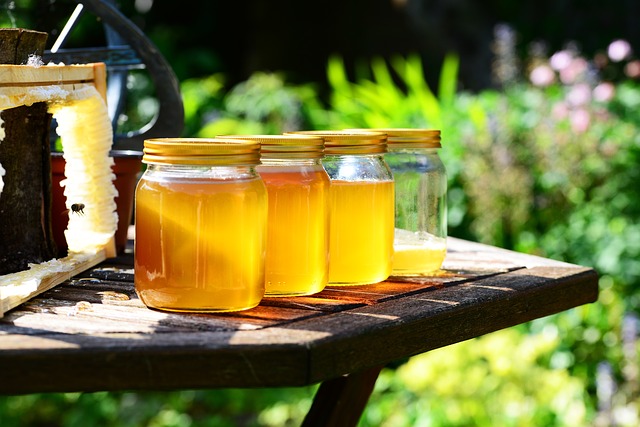 Extracting Honey From Comb into Glass Jars on a Table