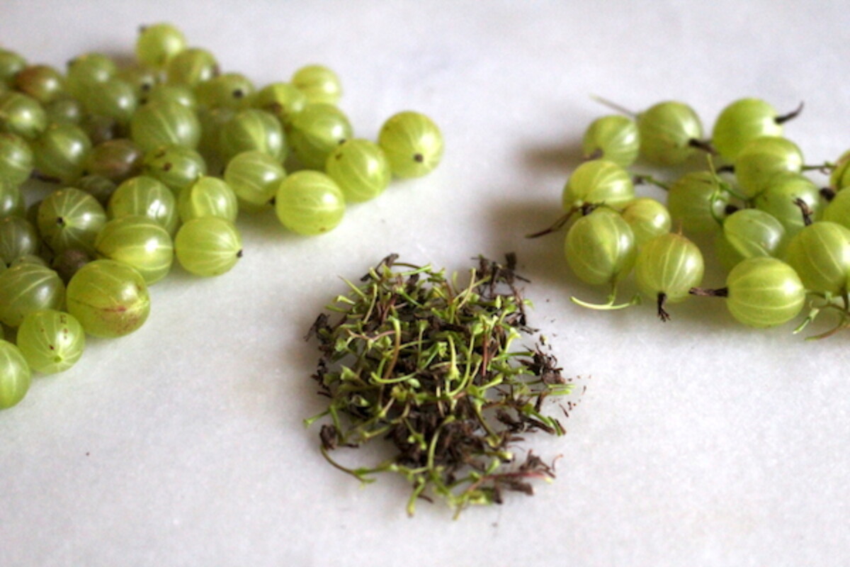 Removing gooseberry tops and tails to clean the fresh berries before making jam.