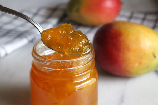 Homemade mango jam on a spoon showing how thick the jam got naturally without pectin.