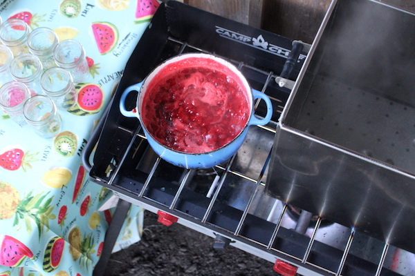Cooking strawberry jam in an outdoor canning kitchen in a dutch oven on a 3 burner stove