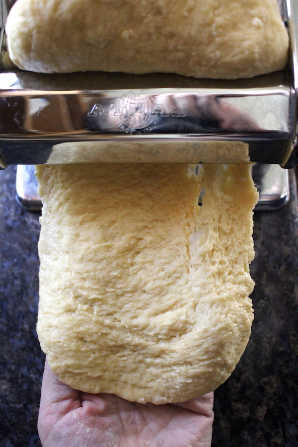 Homemade pasta going through a pasta maker on the first pass