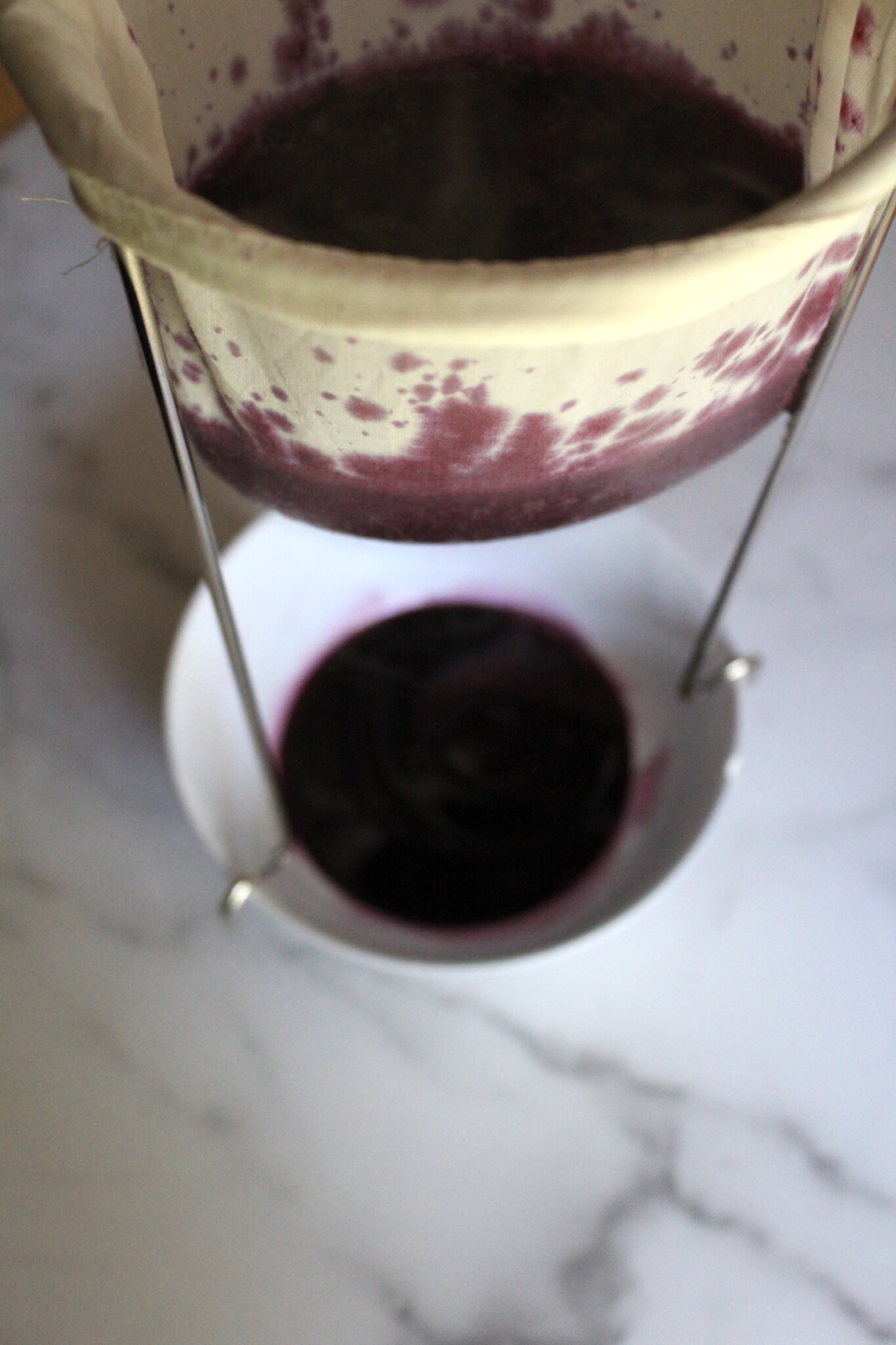 Blueberry juice draining through a jelly bag