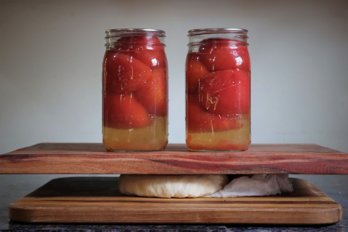 Pressing paneer using an improvised cheese press, made from cutting boards and some home canned tomatoes.
