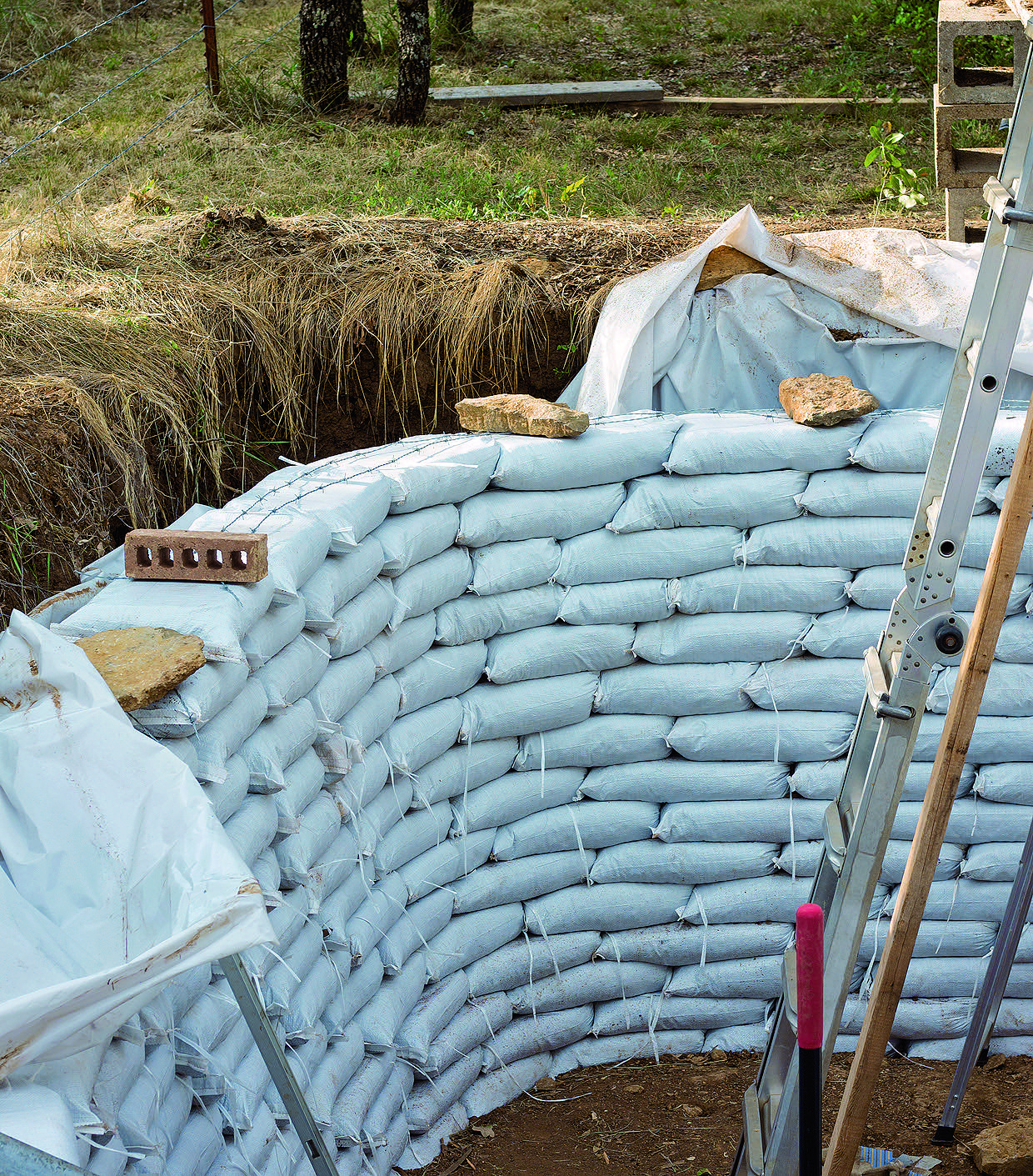 Finishing the earthbag walls. Notice the Barbed Wire strung on top to hold them together.