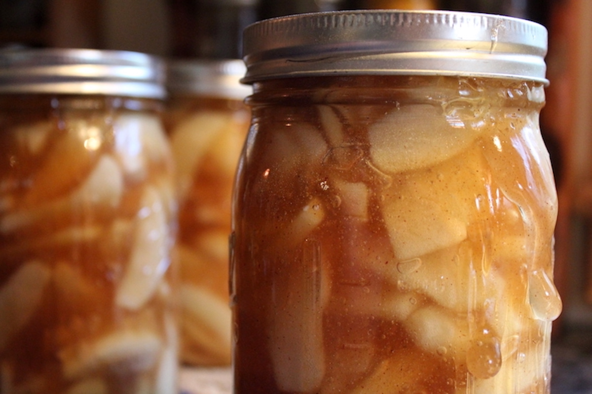Jars of home canned apple pie filling that are siphoning (losing liquid) because they've been taken out of the canner too fast. The filling is oozing down the side of the jar.